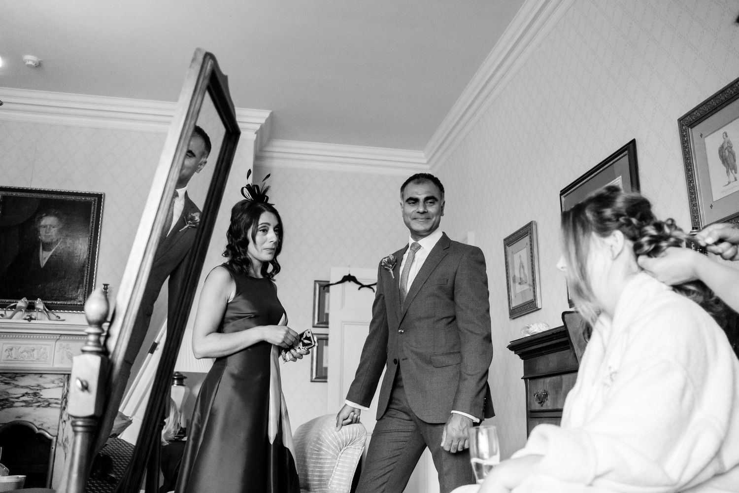 A series of black and white photographs showing a wedding party preparing and celebrating in various indoor settings.