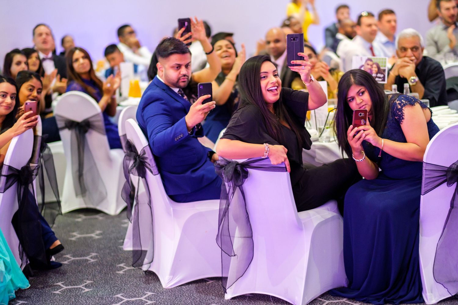 Wedding guests using phones to capture moments during the celebration.