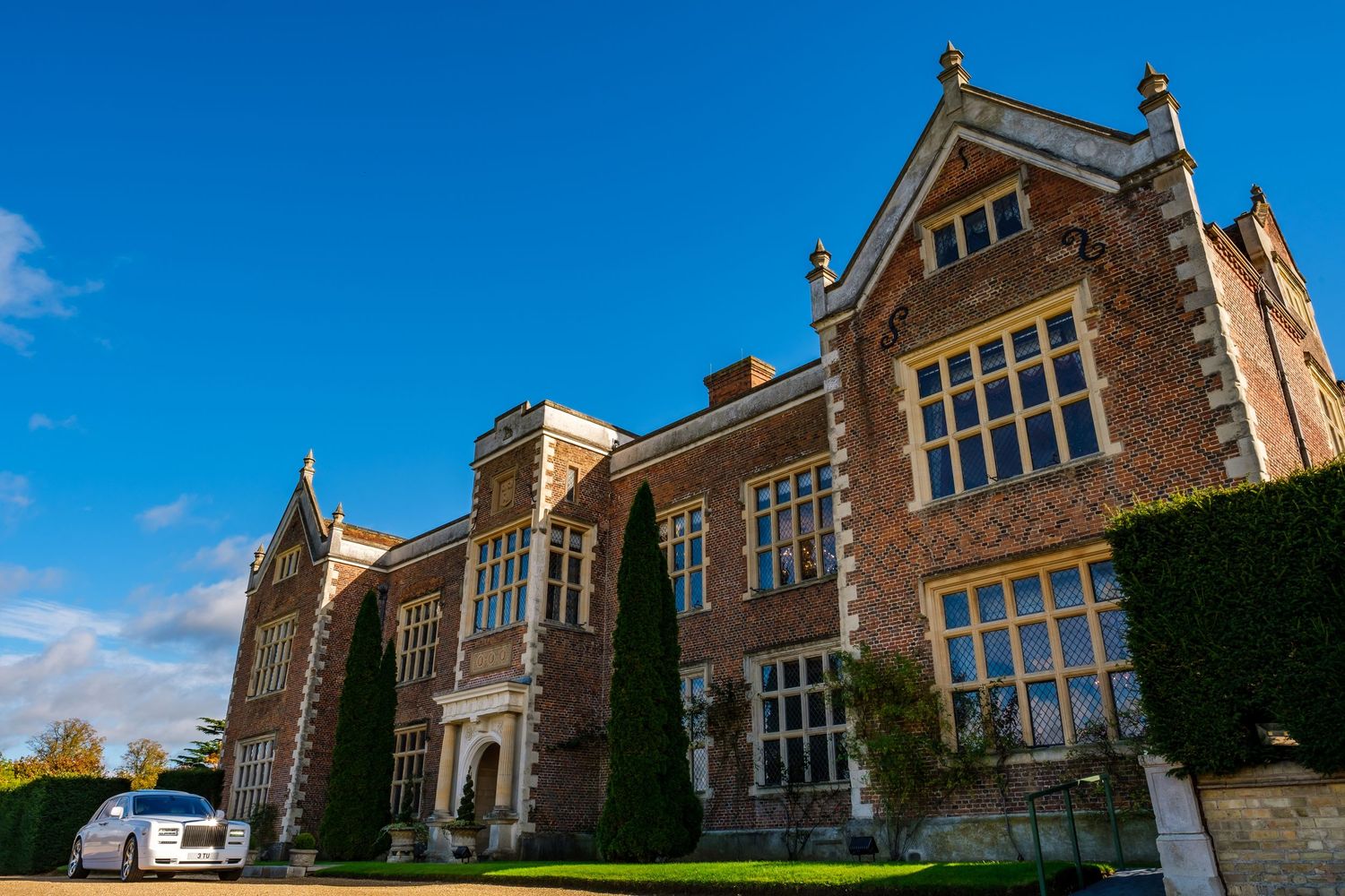 Historic brick mansion with large windows and ornate architectural details against bright blue sky.