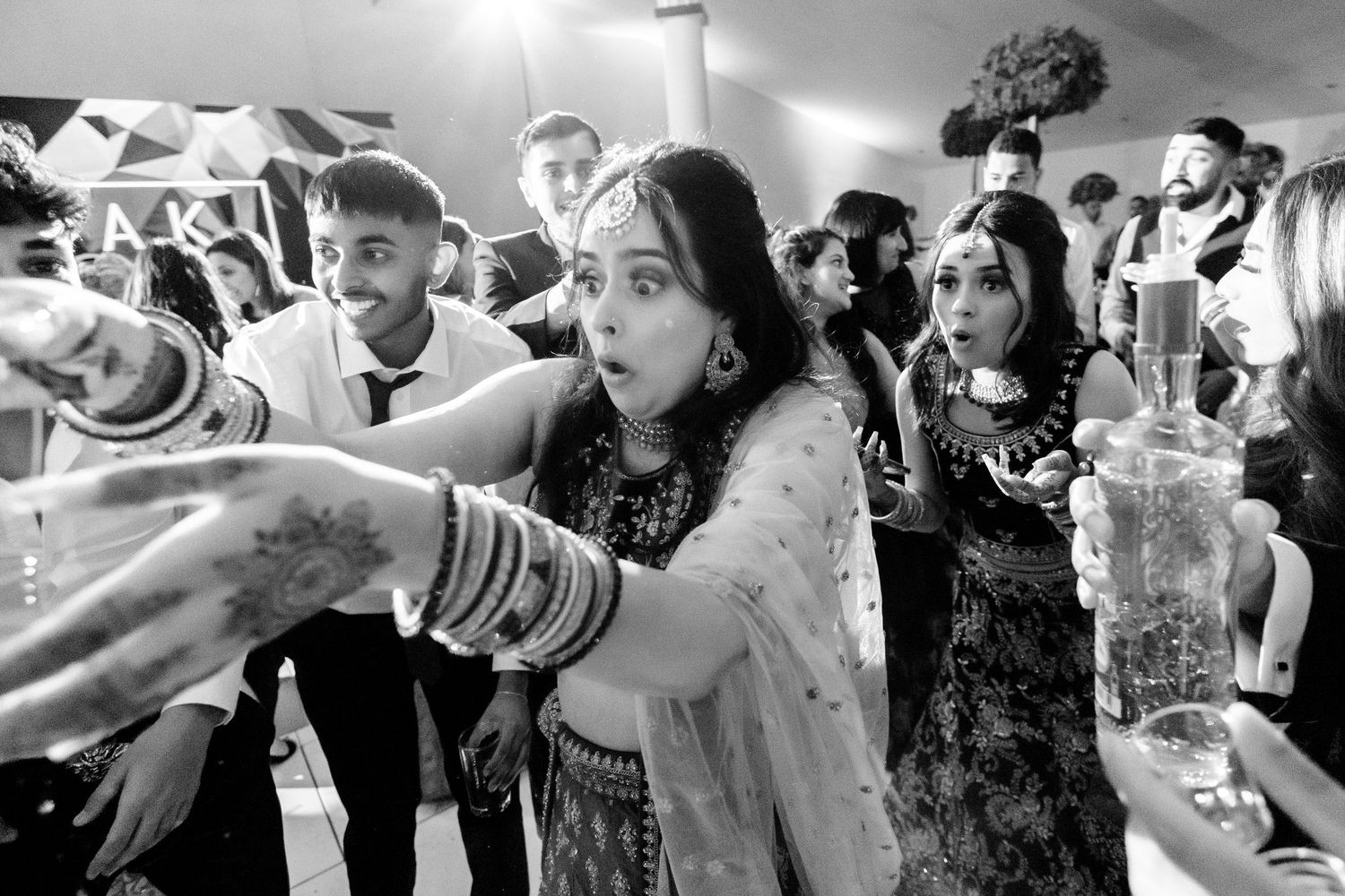 A group of people drinking from bottles in a party setting, captured in black and white photography.
