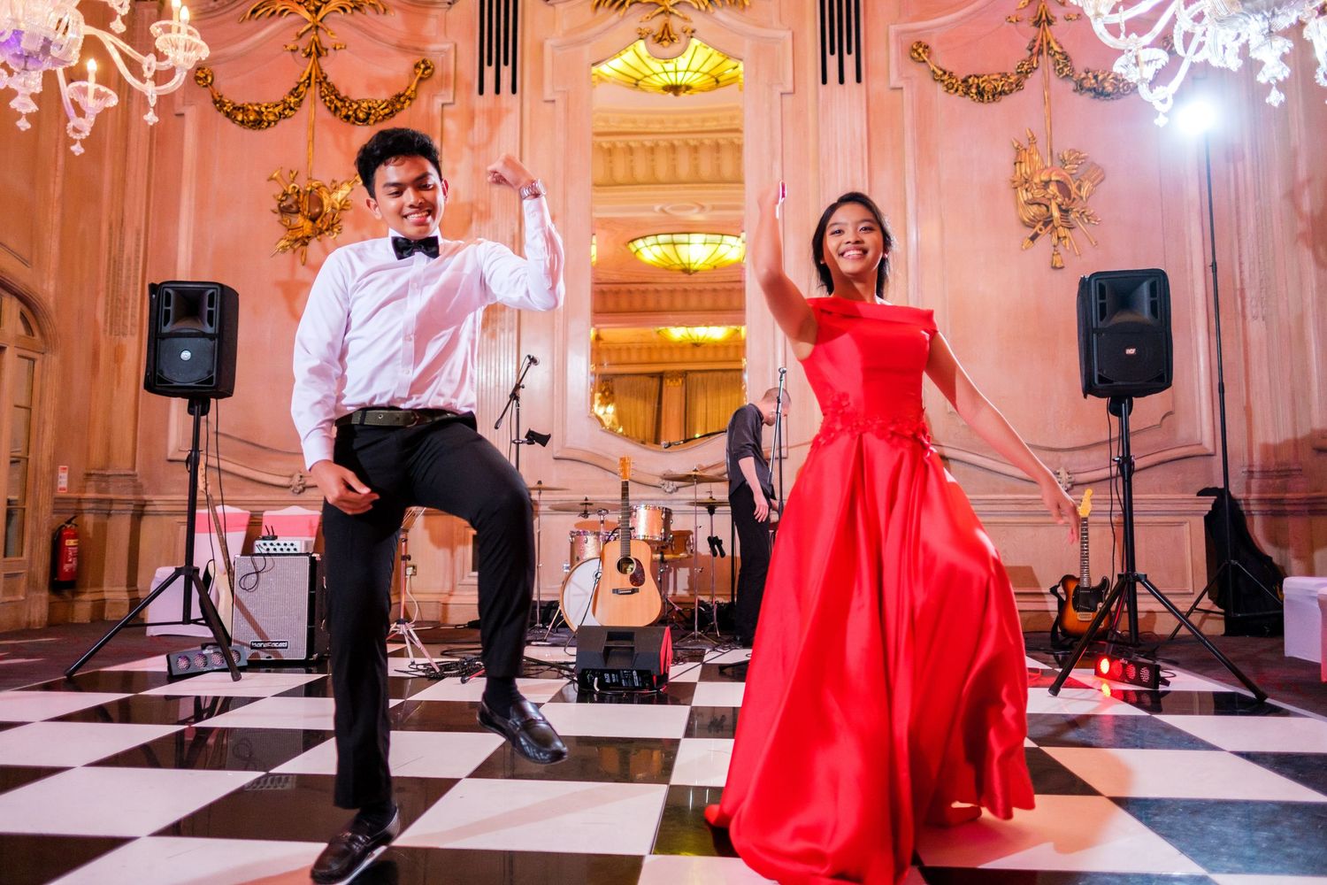 Wedding reception dance floor with pink lighting and black and white checkered floor.