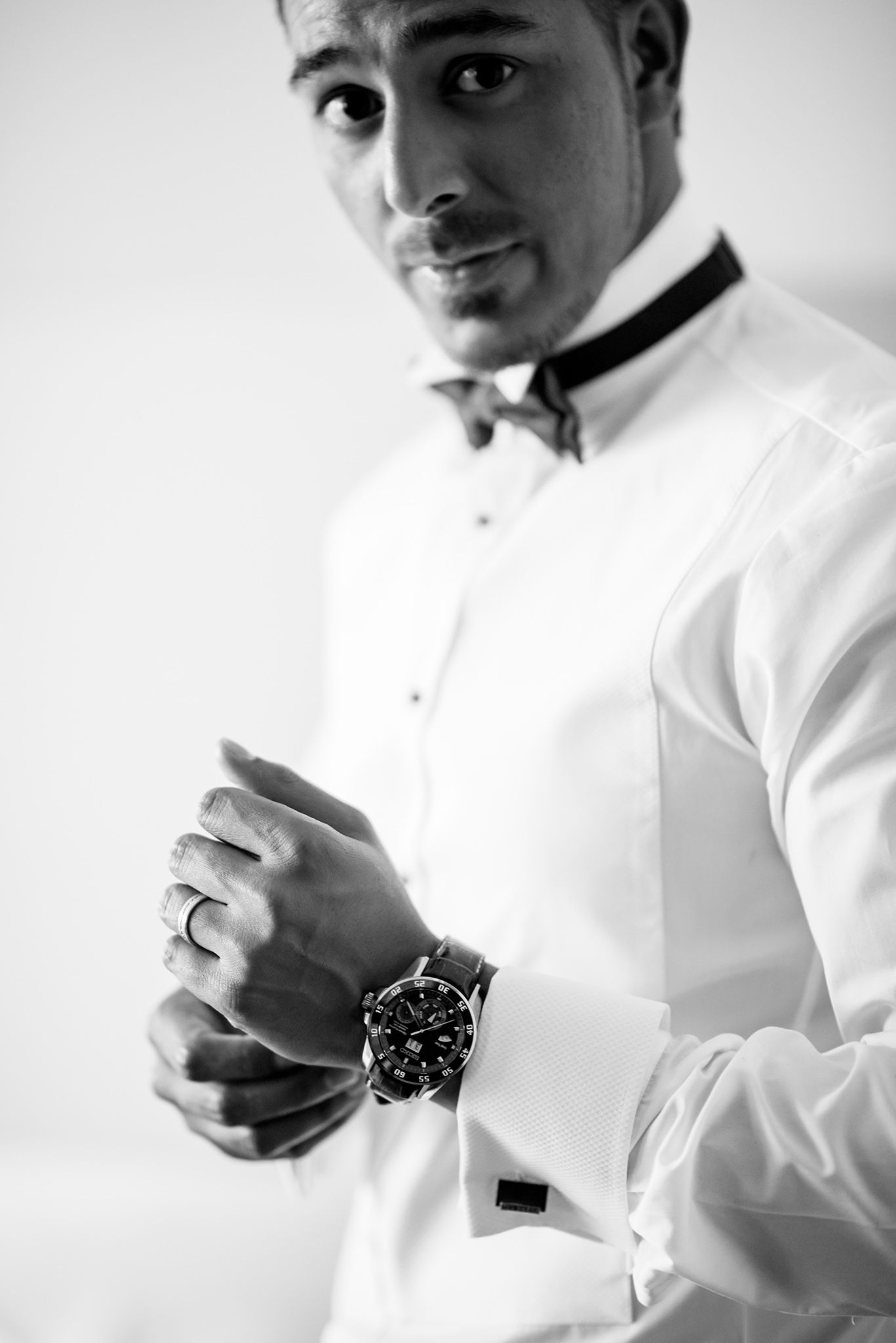 Close-up black and white photos of hands fastening shirt buttons and adjusting cuffs.