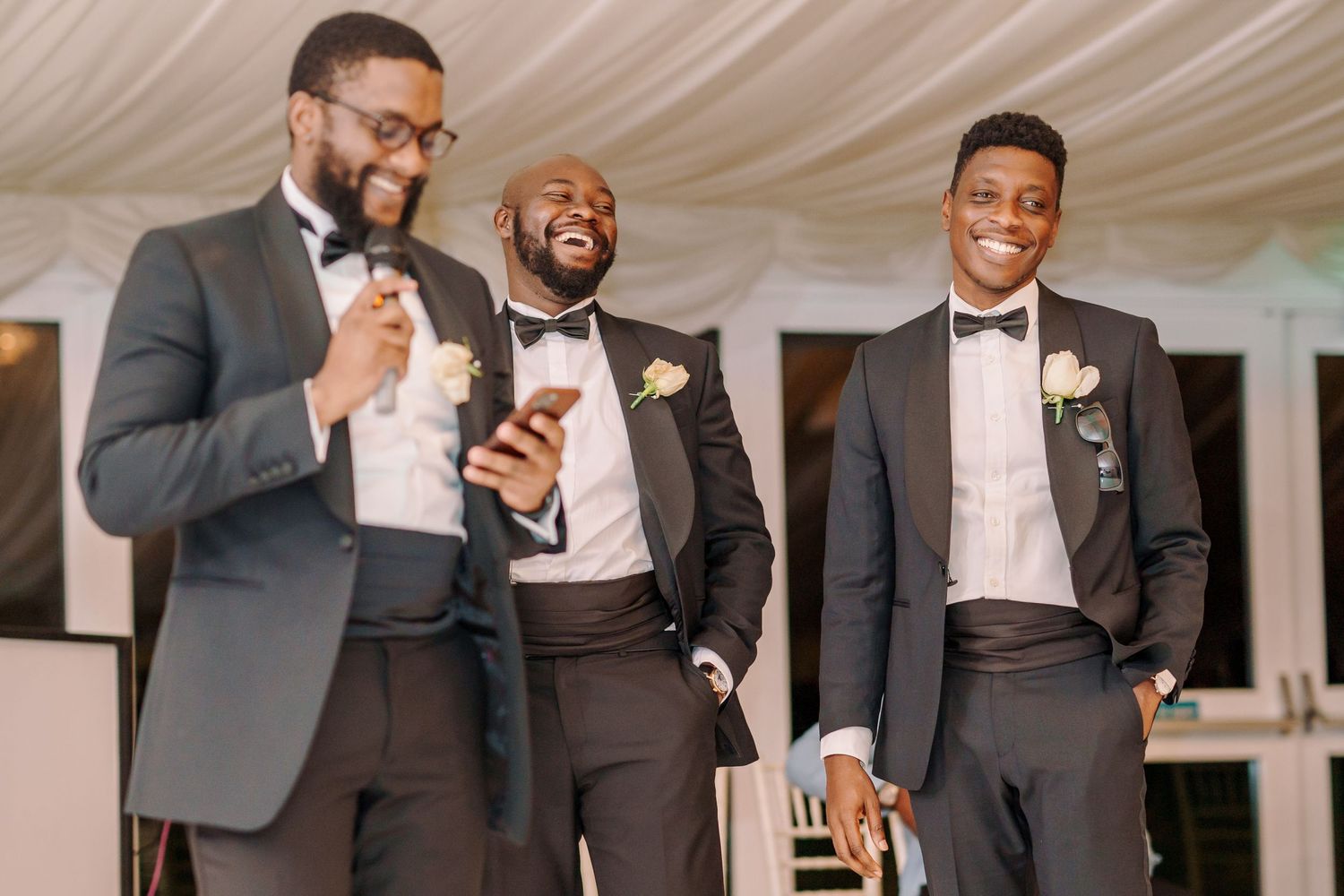 Groomsmen in dark suits and bowties gather during wedding reception celebrations.