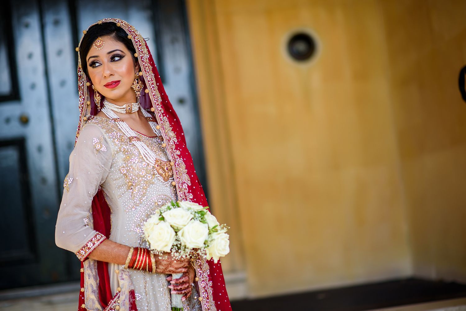 Close-up bridal portrait showcasing traditional South Asian wedding jewelry and bouquet.