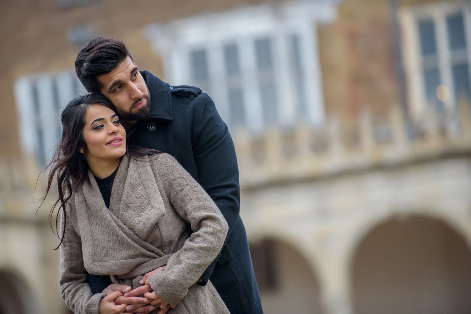 Romantic moment captured against classic architectural backdrop with arched windows.