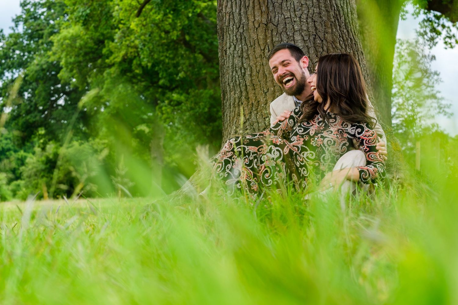 People laughing and having fun while hiding behind trees in a lush green summer forest setting.