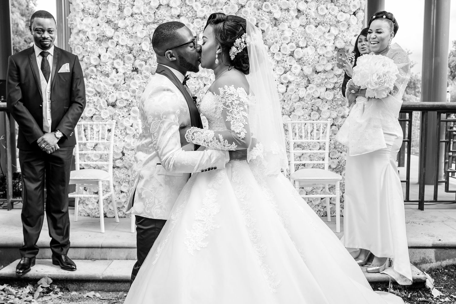 Beautiful outdoor wedding ceremony with decorative floral wall backdrop.