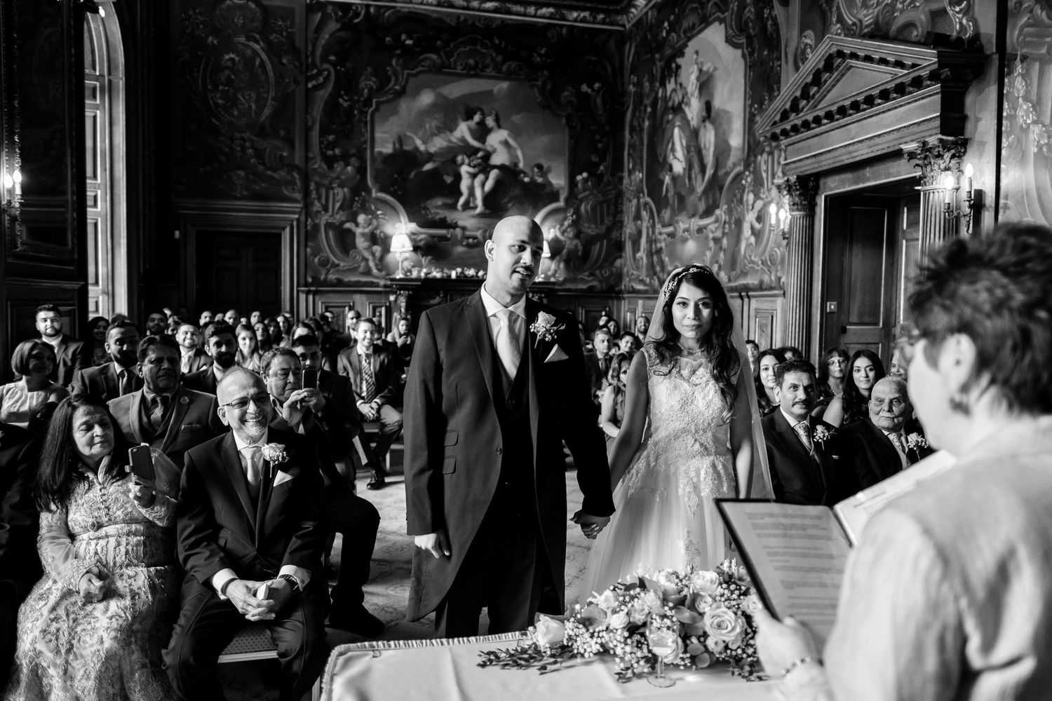 Panoramic view of wedding ceremony in a luxurious ballroom with ornate details.