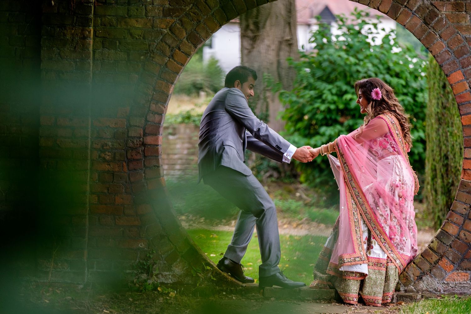 Romantic outdoor couple photoshoot in a garden setting with pink floral details.