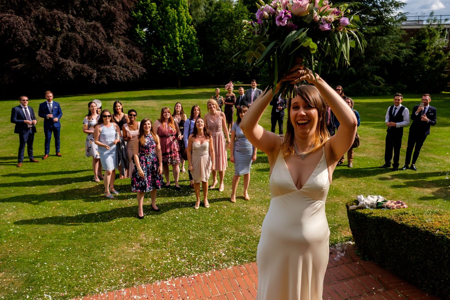 Guests gather on a sunny lawn for an elegant outdoor wedding celebration.