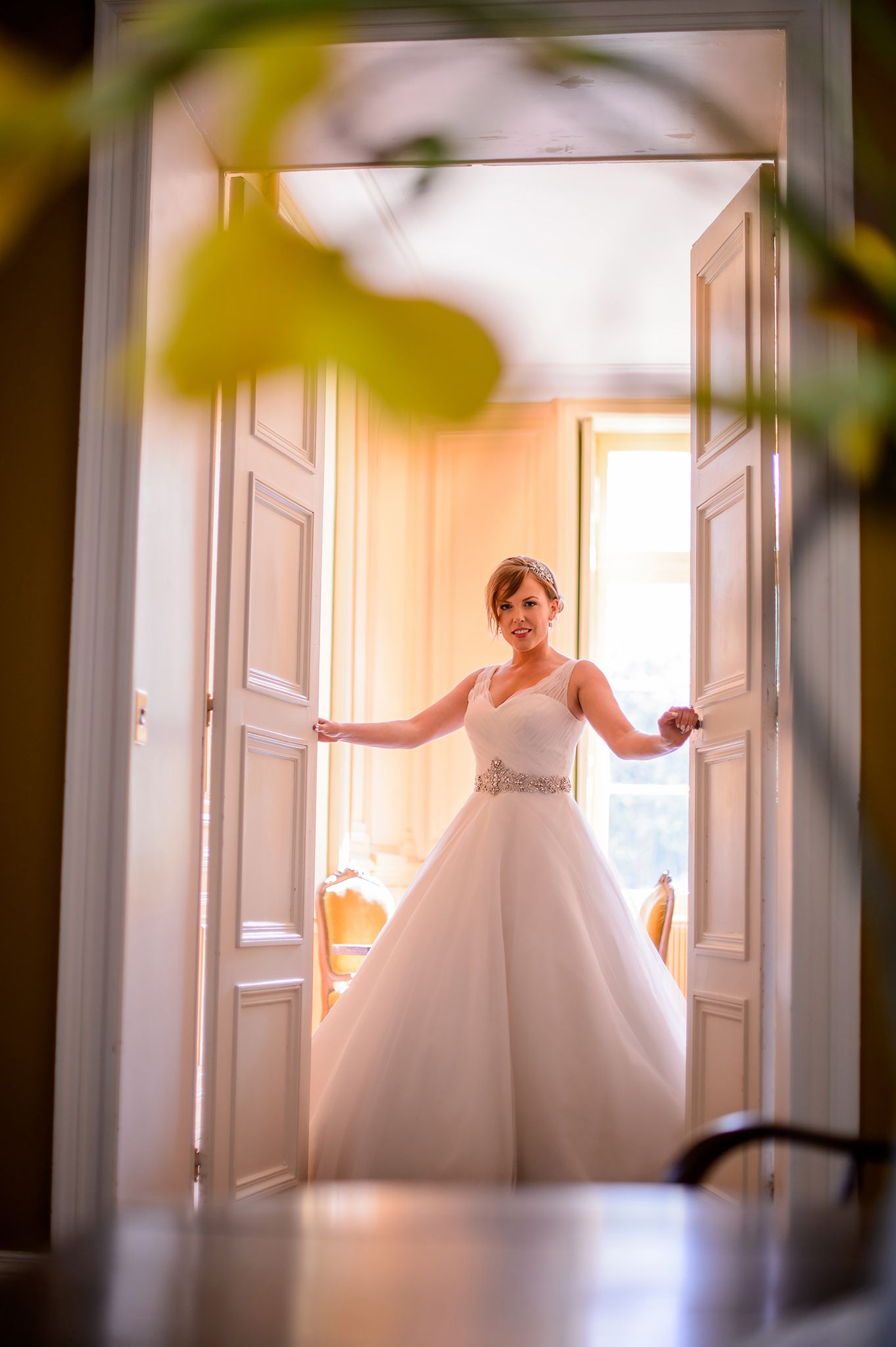 Ethereal wedding photos through doorways in sunlit hallway with white doors.