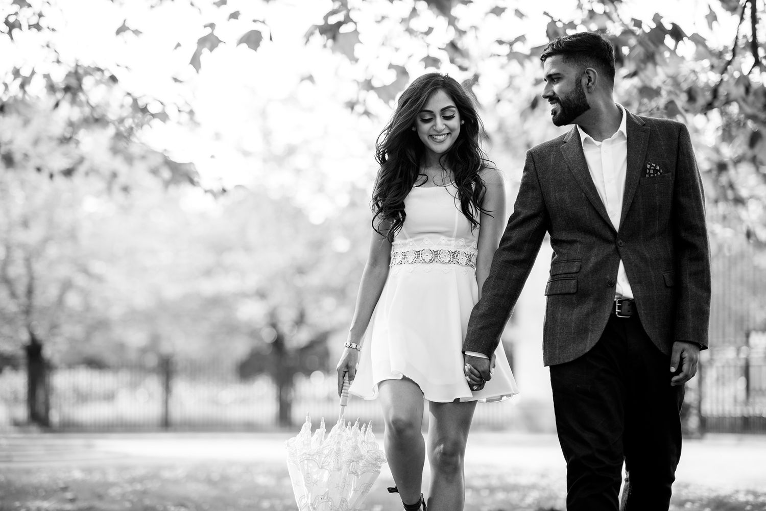 Elegant black and white portraits showcase a romantic couple walking through a park.