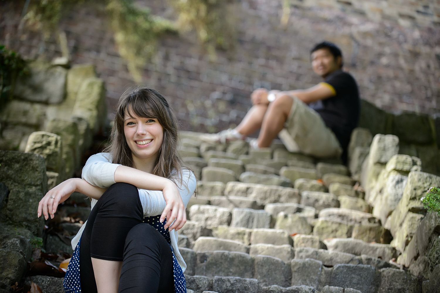 Couple sitting together on stone steps in an outdoor setting.