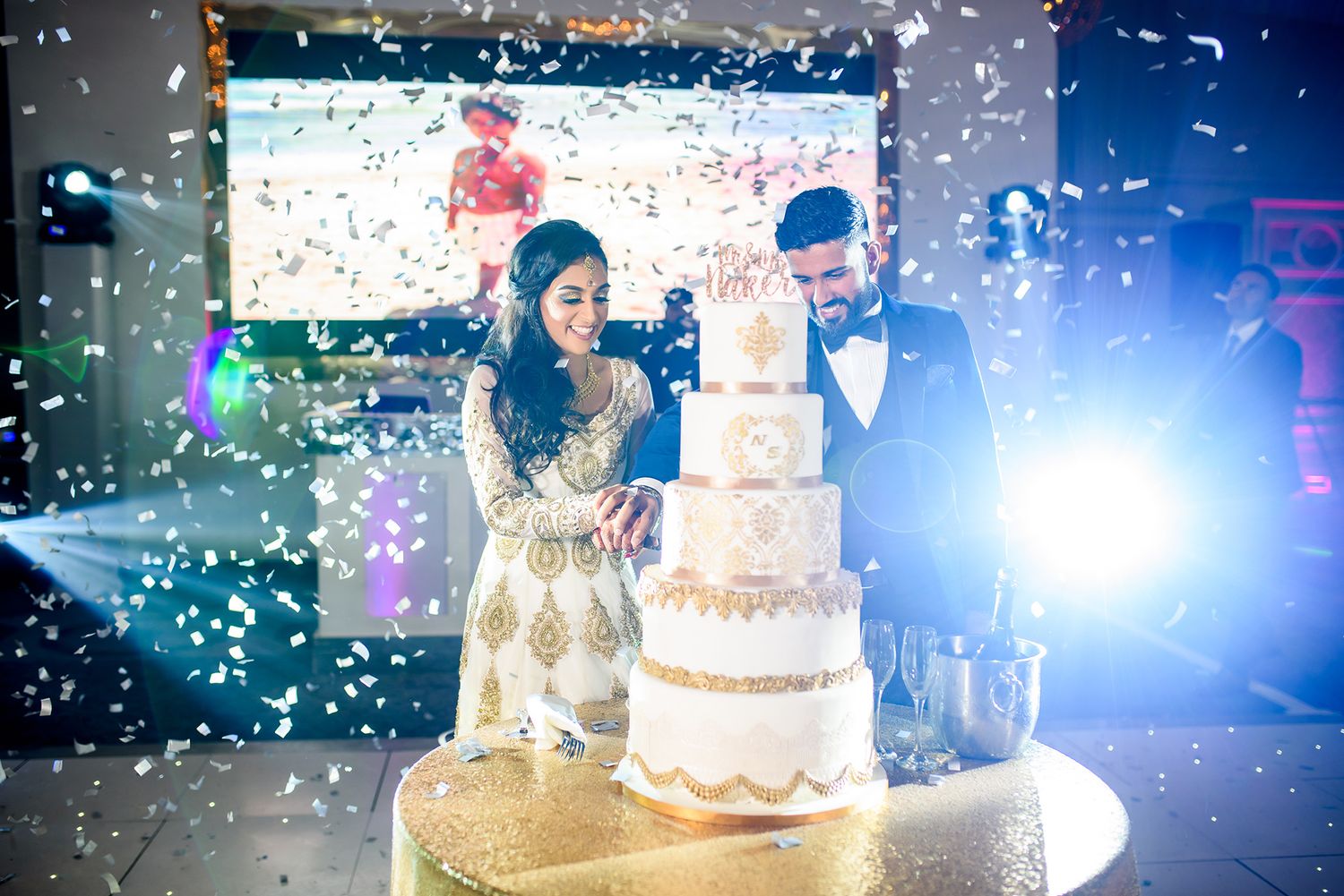 Wedding celebration with confetti falling around a beautifully lit cake display.