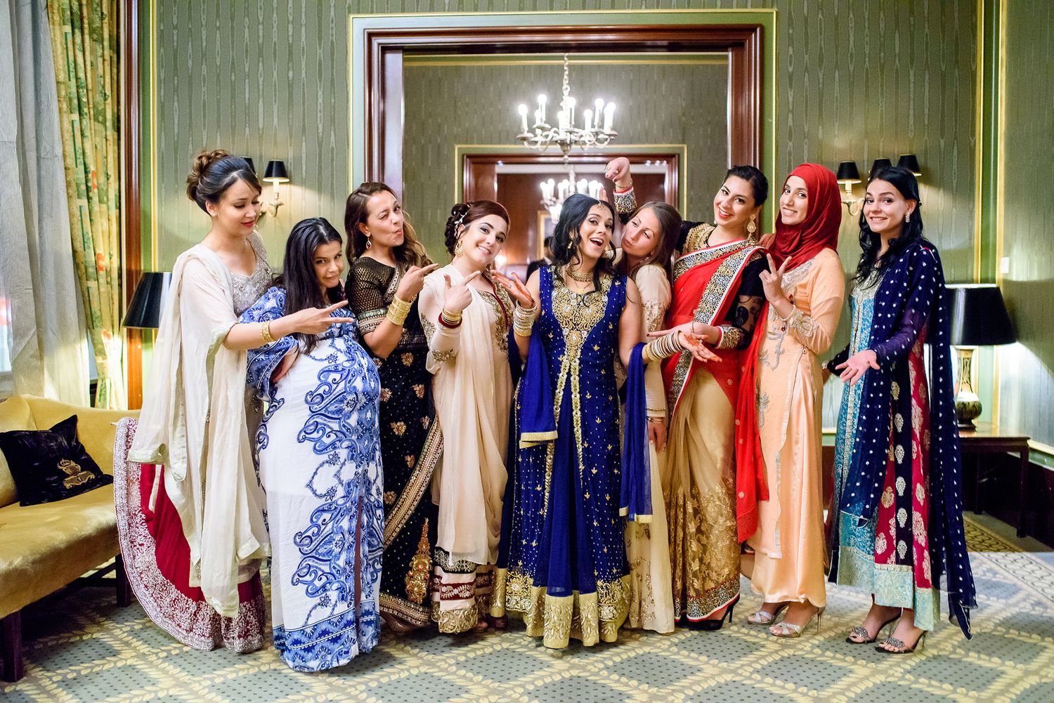 Wedding guests in colorful traditional South Asian attire pose together for group photos.