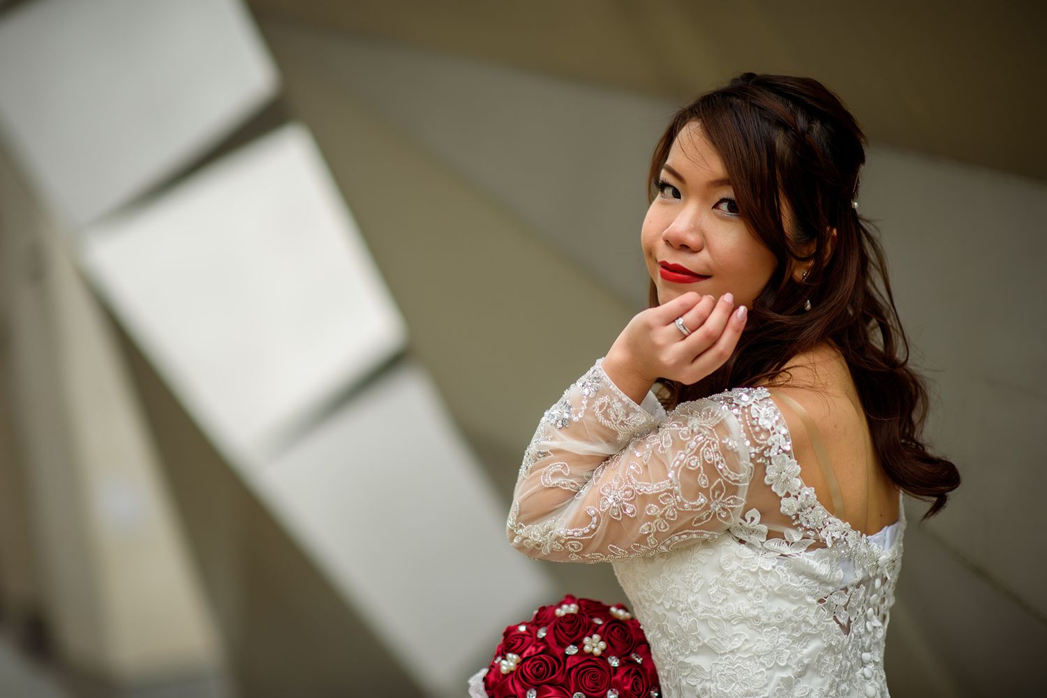 South Asian bride in traditional wedding attire with elegant lace details and jewelry against soft lighting.
