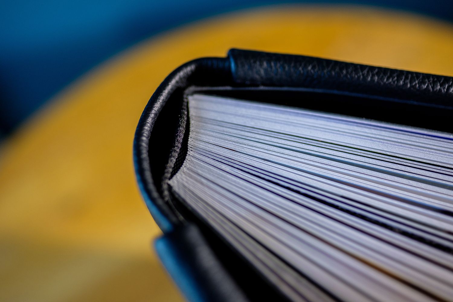 Close-up view of book pages with shallow depth of field against blue and yellow background.