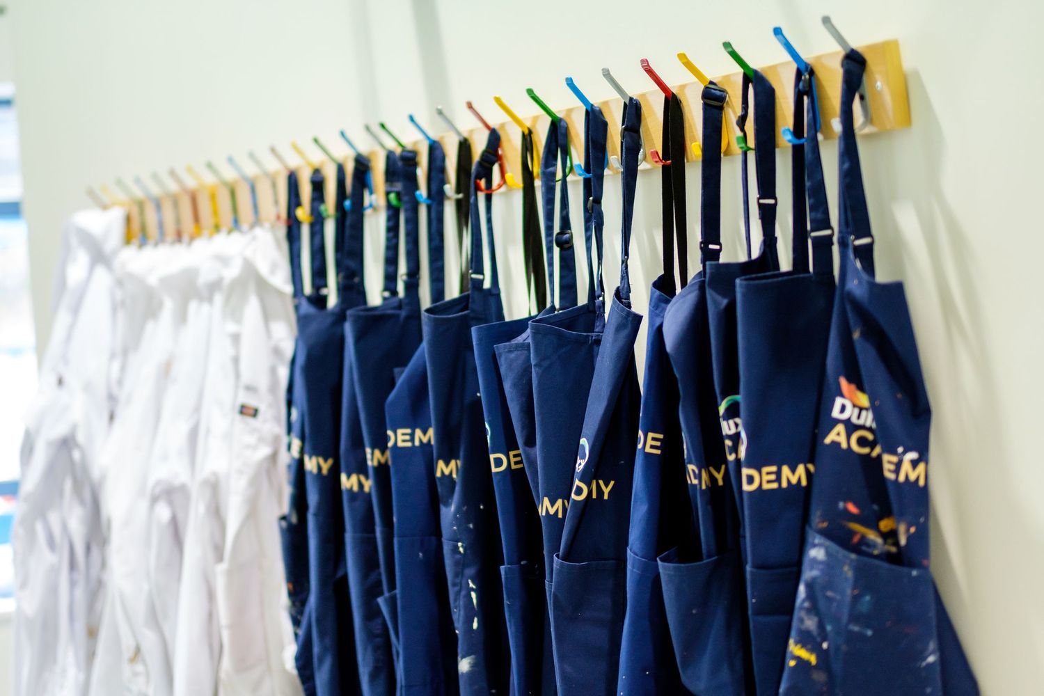 Row of navy blue formal garments hanging neatly on clothing hangers.
