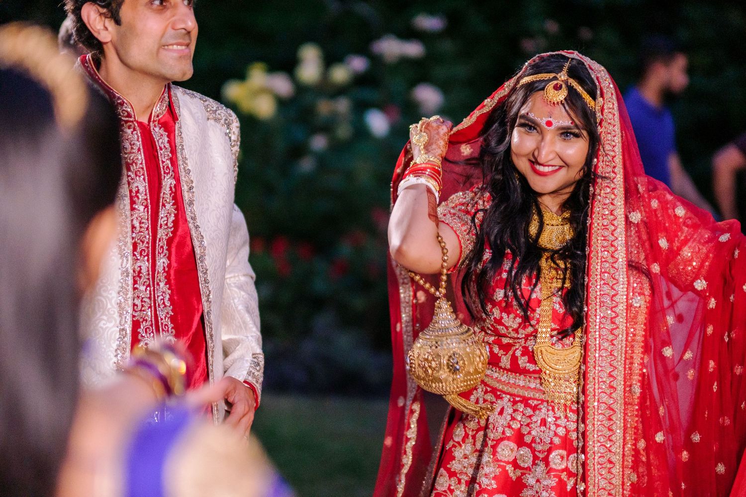 Outdoor wedding ceremony with traditional Indian attire and decorative elements in natural setting.