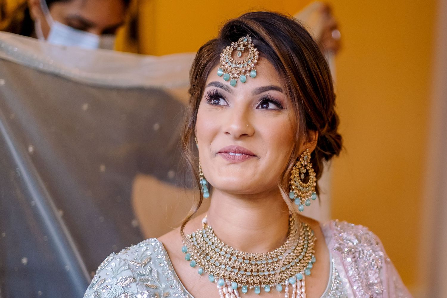 Bride wearing ornate jewelry and traditional South Asian bridal attire.
