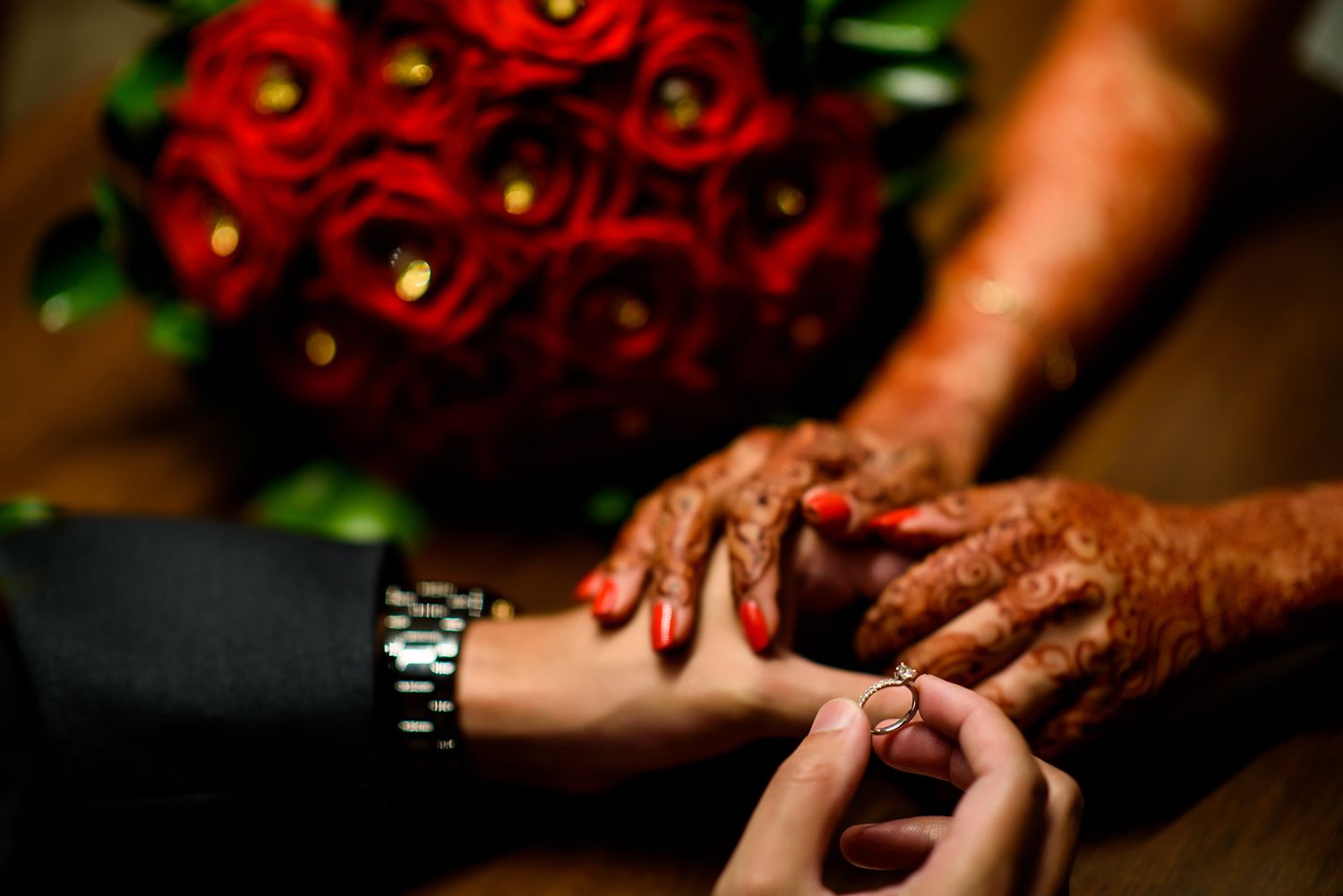 Detailed shot of traditional henna designs with red roses in the background.