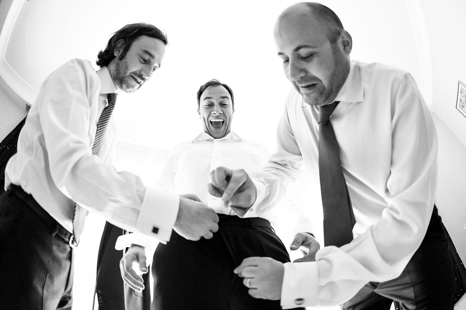 Black and white photo of groomsmen laughing and dancing together.