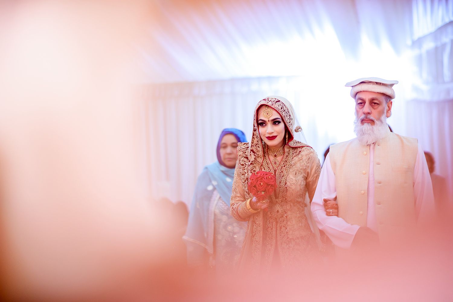 A soft-focus ceremonial moment captured through a pink-tinted filter.