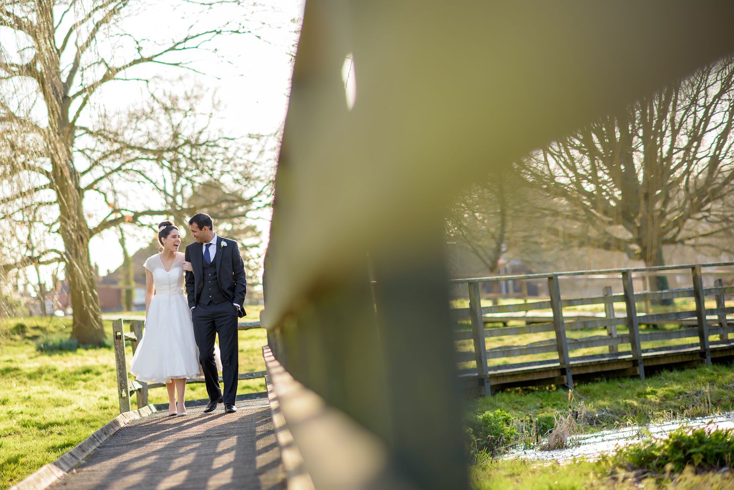 Elegant wedding couple poses together in a scenic outdoor garden setting with soft natural lighting.