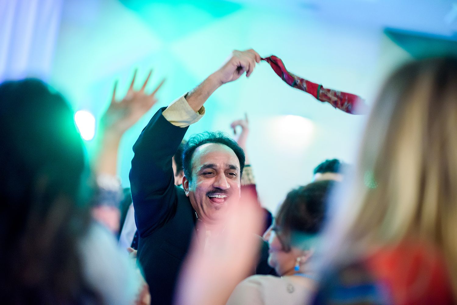Festive dance celebration with blue lighting and raised hands in celebration.