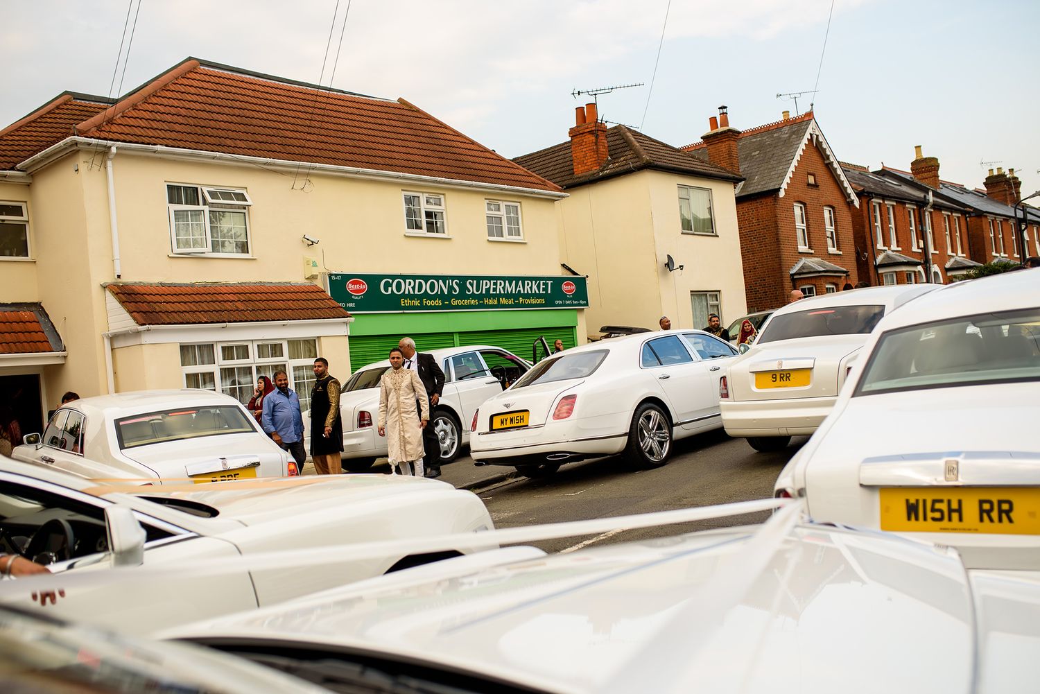 Row of white luxury cars and limousines parked outside a residential area.