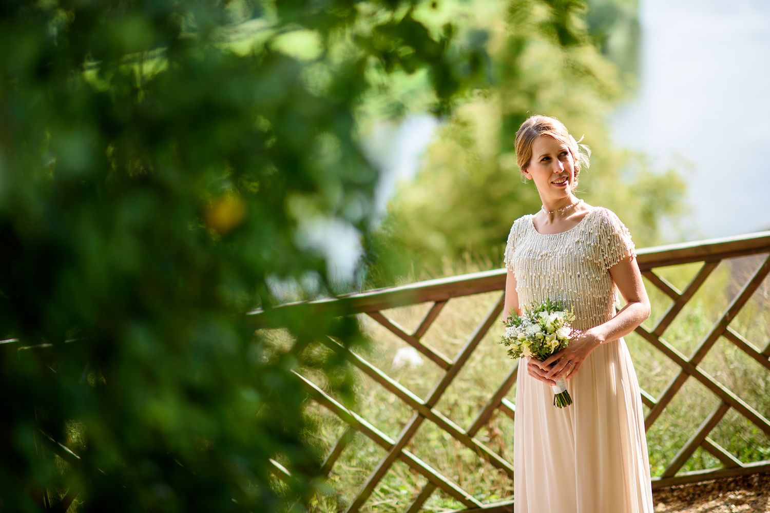 Elegant wedding portraits in sunny garden setting with rustic wooden fence backdrop.