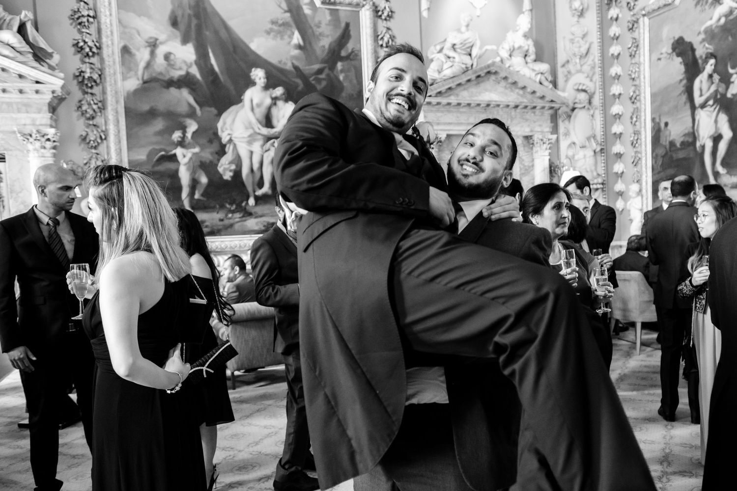 Wedding party members dance and celebrate during an outdoor reception.