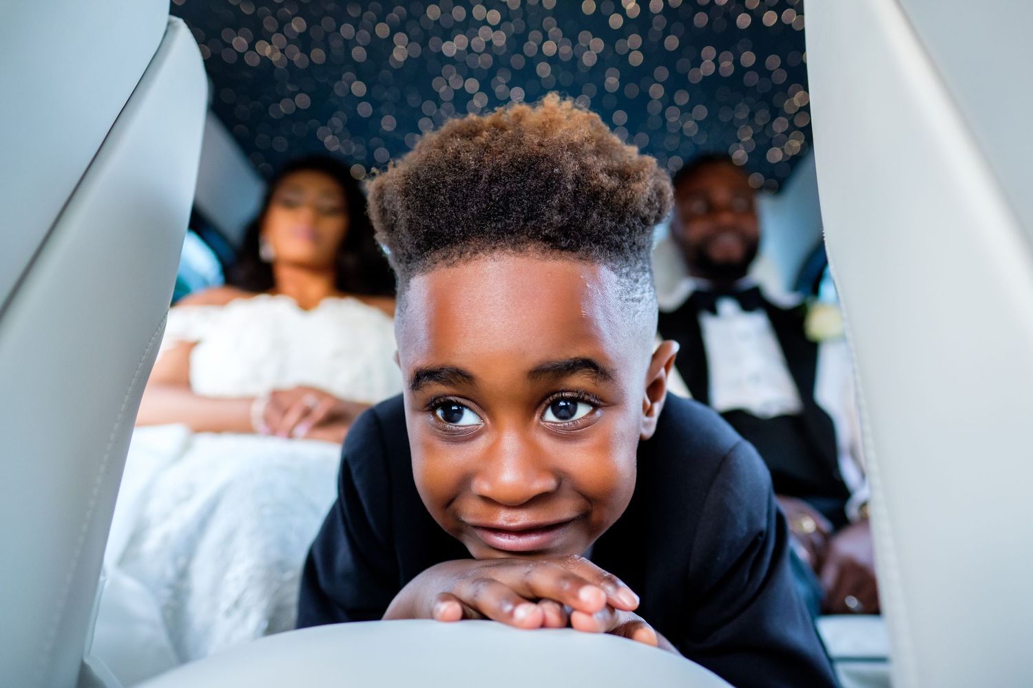 Children peek and smile playfully during a formal wedding event.