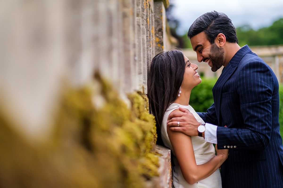 Romantic moment shared between couple against an aged stone wall with moss.