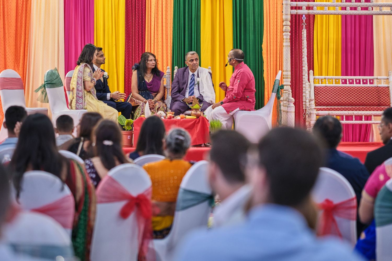 A colorful Indian wedding ceremony with bright fabric decorations and guests gathered in traditional attire.