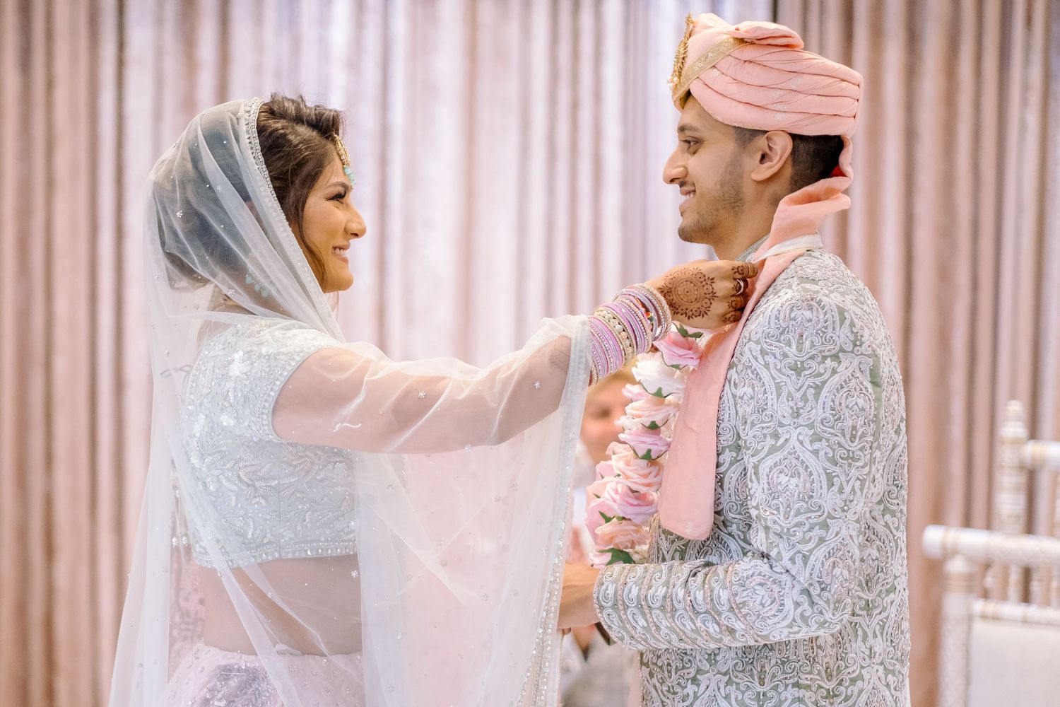 Traditional wedding ceremony with elegant decor and pink curtain backdrop.