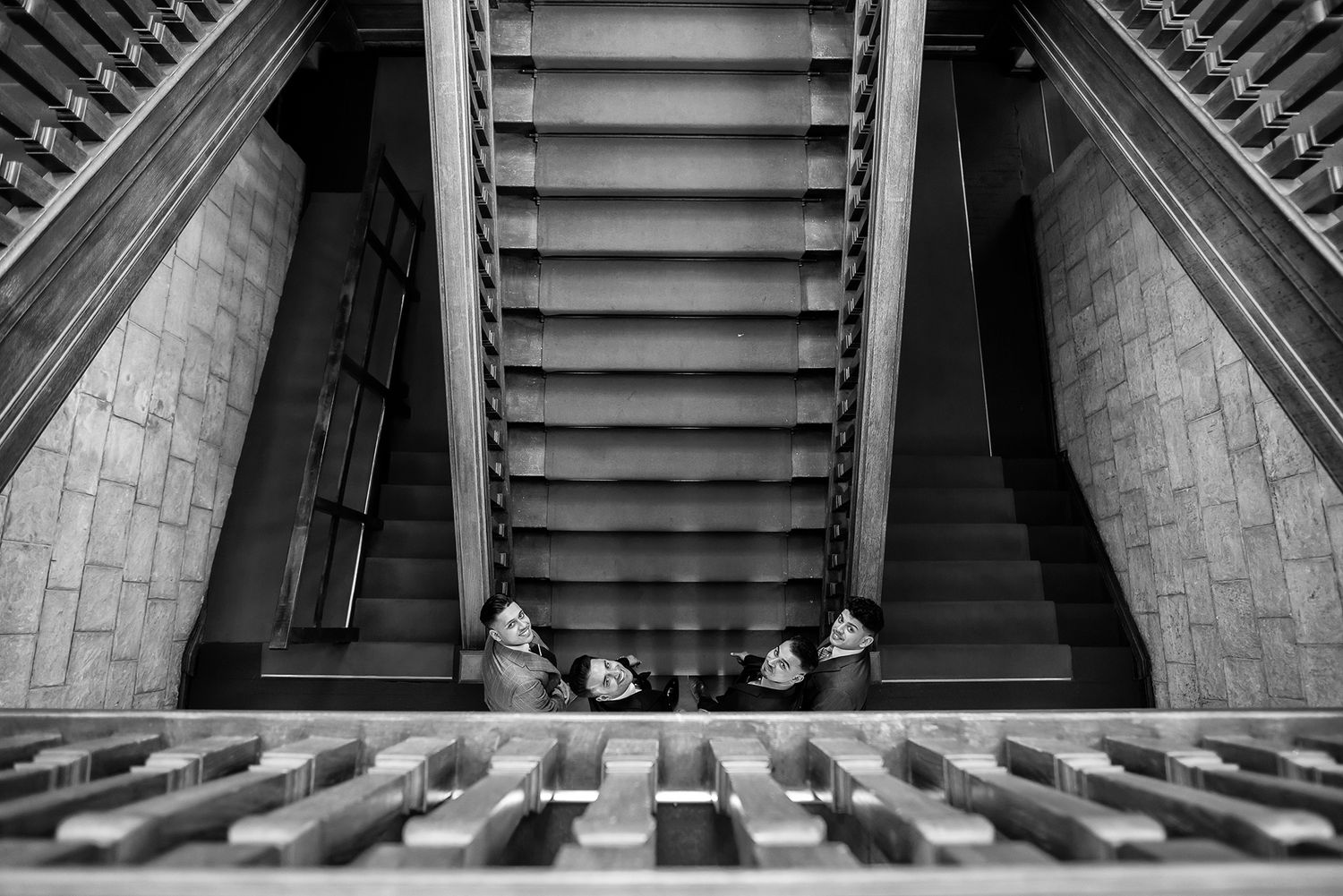 Aerial view looking down stone staircase with people gathered at bottom in black and white.