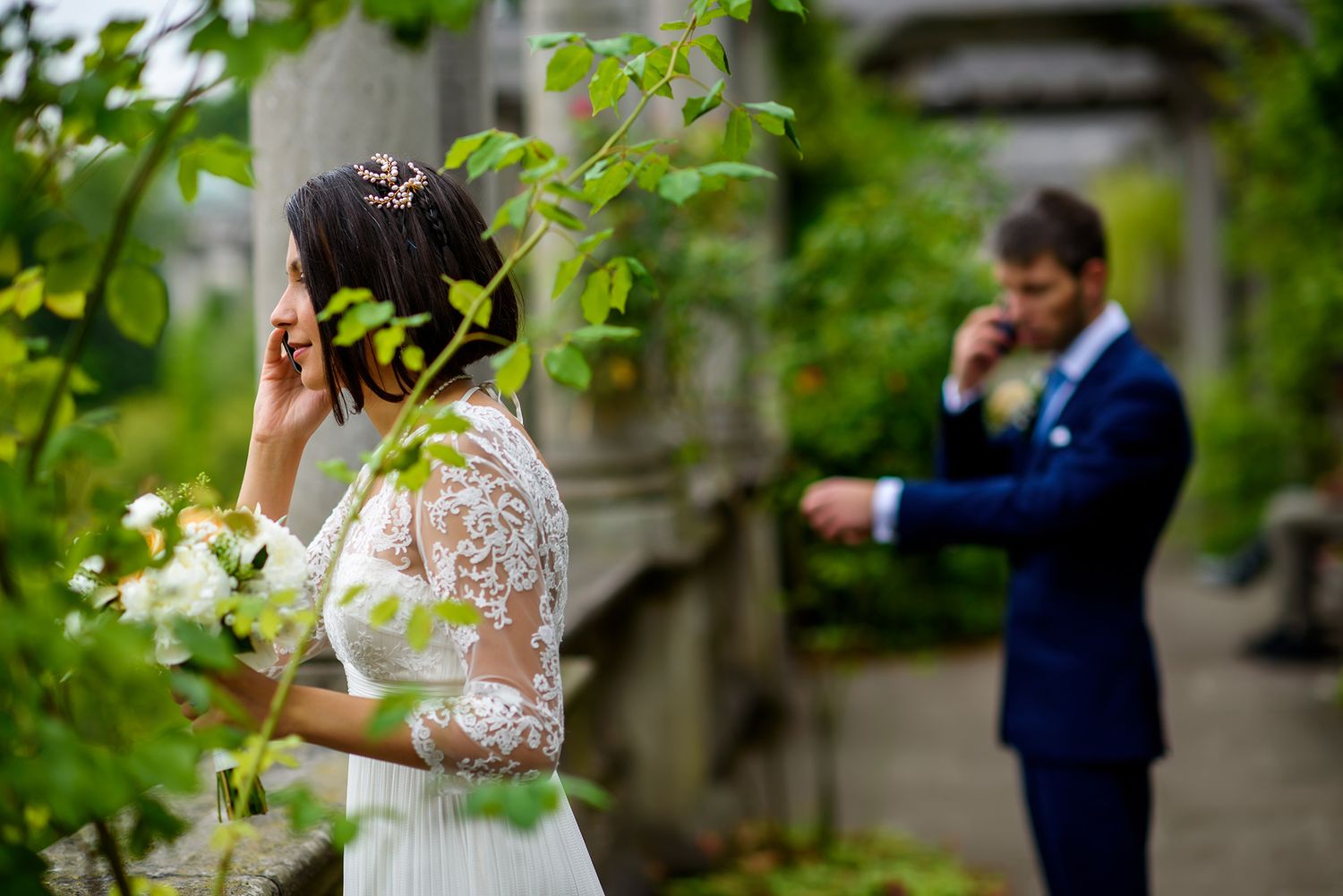 Couple shares intimate moment among garden columns and climbing vines.