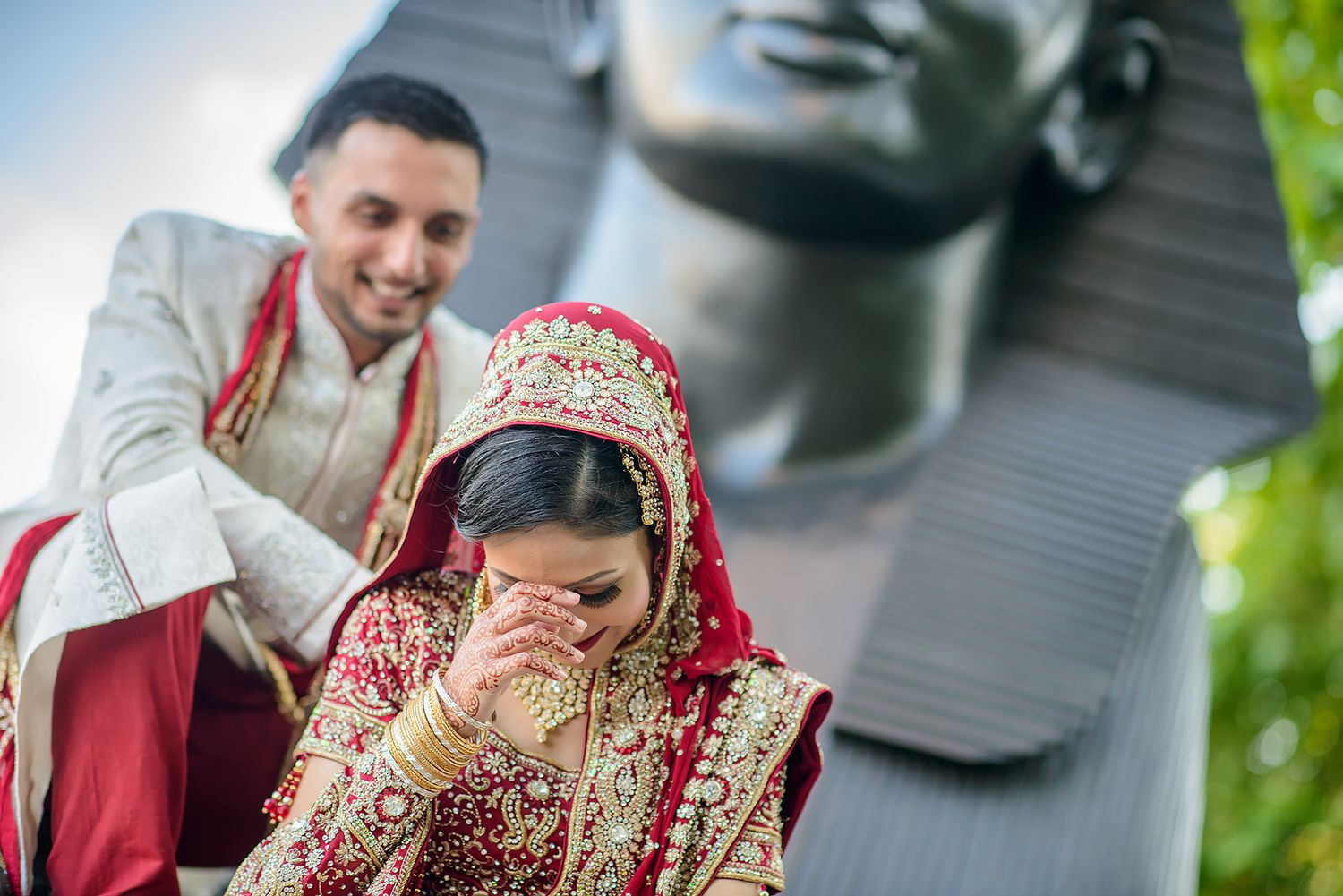 Candid wedding moment captured outdoors with natural greenery backdrop.