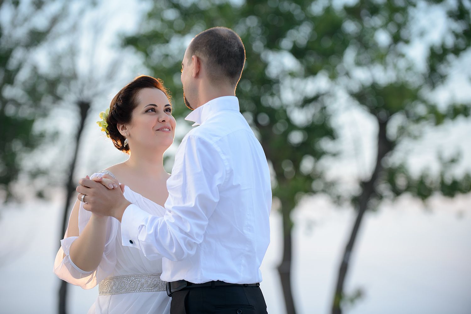A couple sharing an intimate dance moment outdoors with trees in the background.