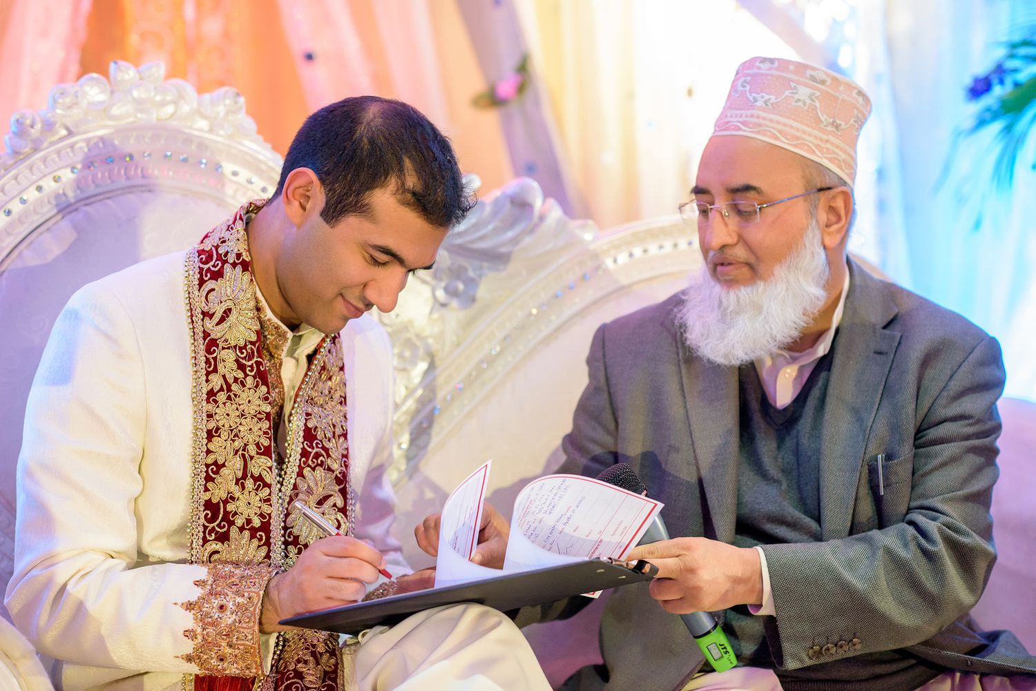 Traditional Indian wedding ceremony with participants seated on decorative stage.