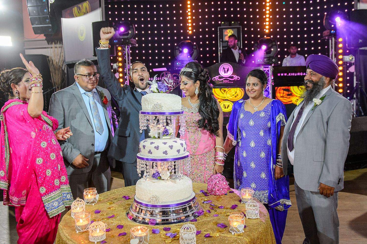 Elegant wedding reception with purple lighting and tiered cake display.