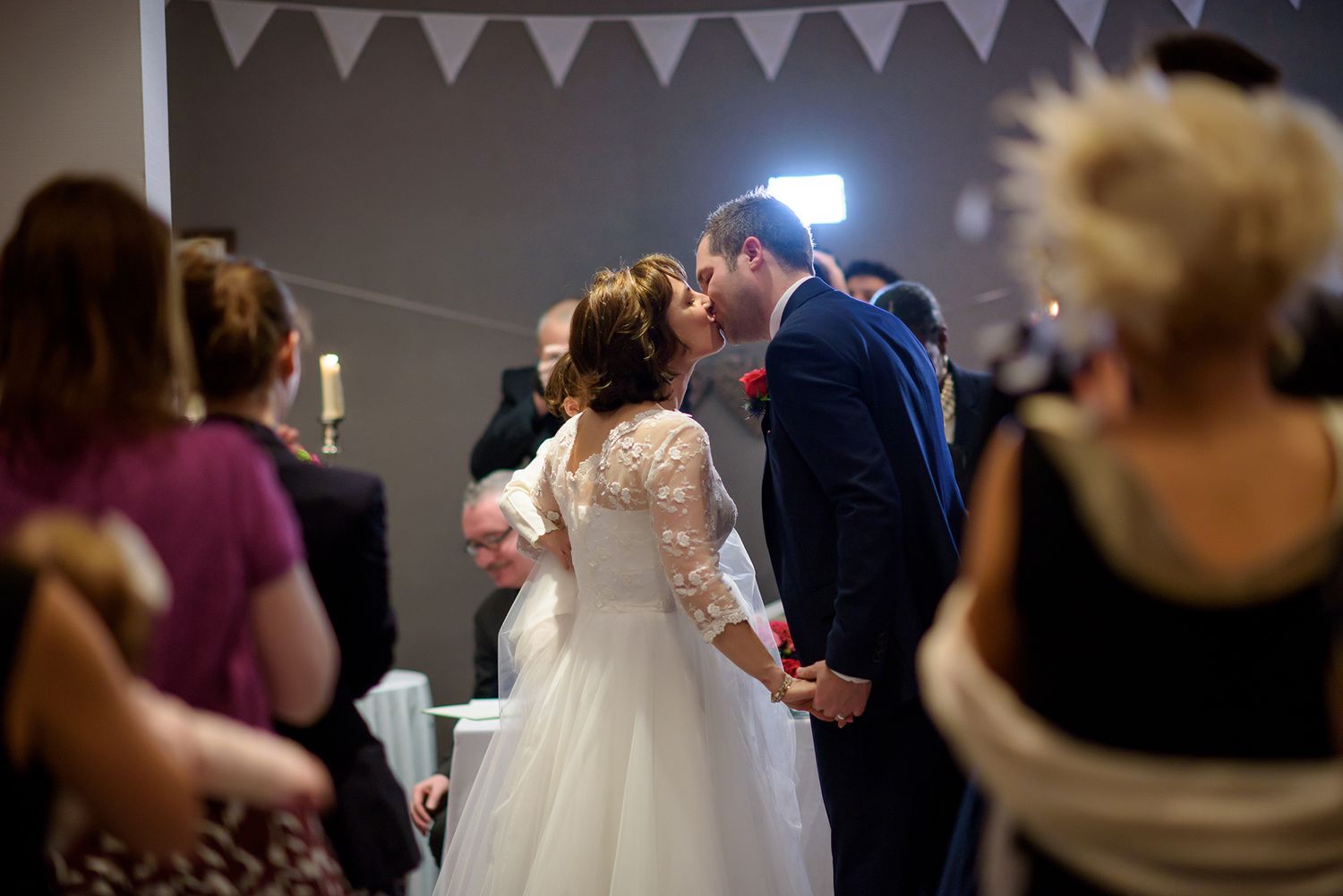 White bunting decorates wedding reception space with guests celebrating.