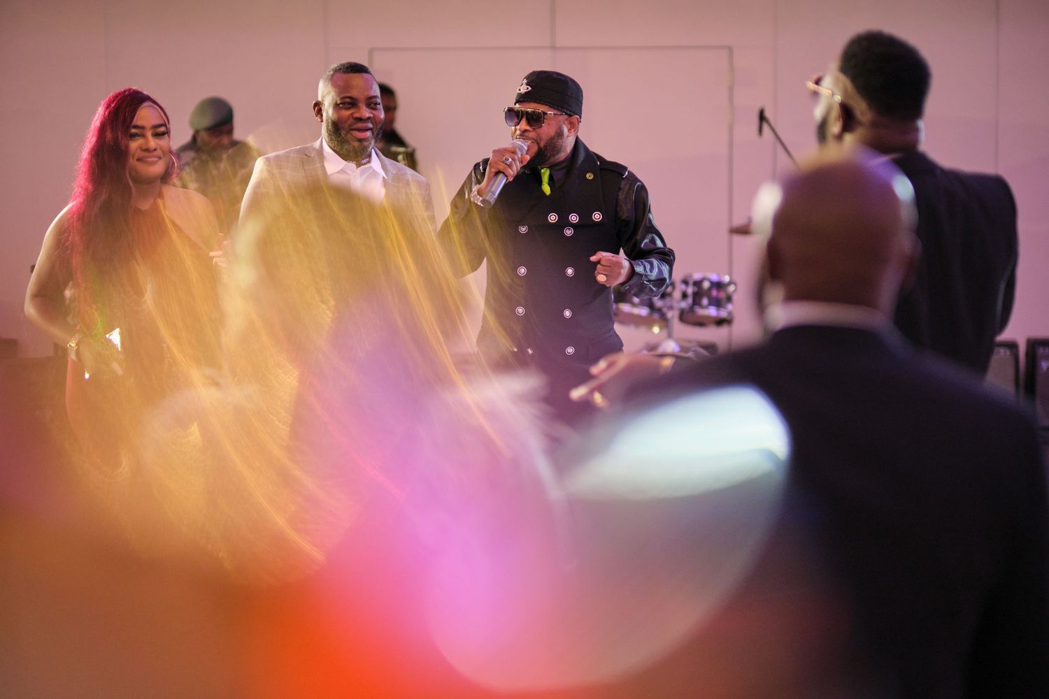 Party guests enjoying themselves on a dance floor illuminated by pink ambient lighting.