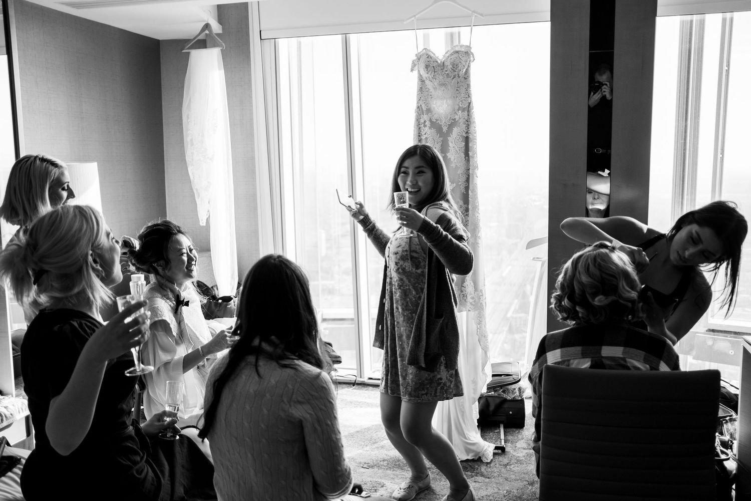 A series of silhouetted figures stand against bright windows in a black and white panoramic composition.