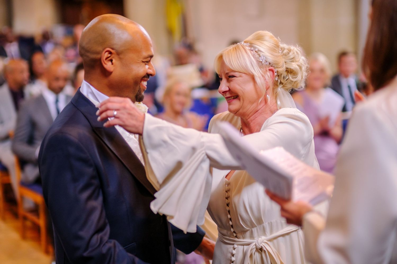 Wedding guests gathered in a church celebrate during an emotional moment at the ceremony.