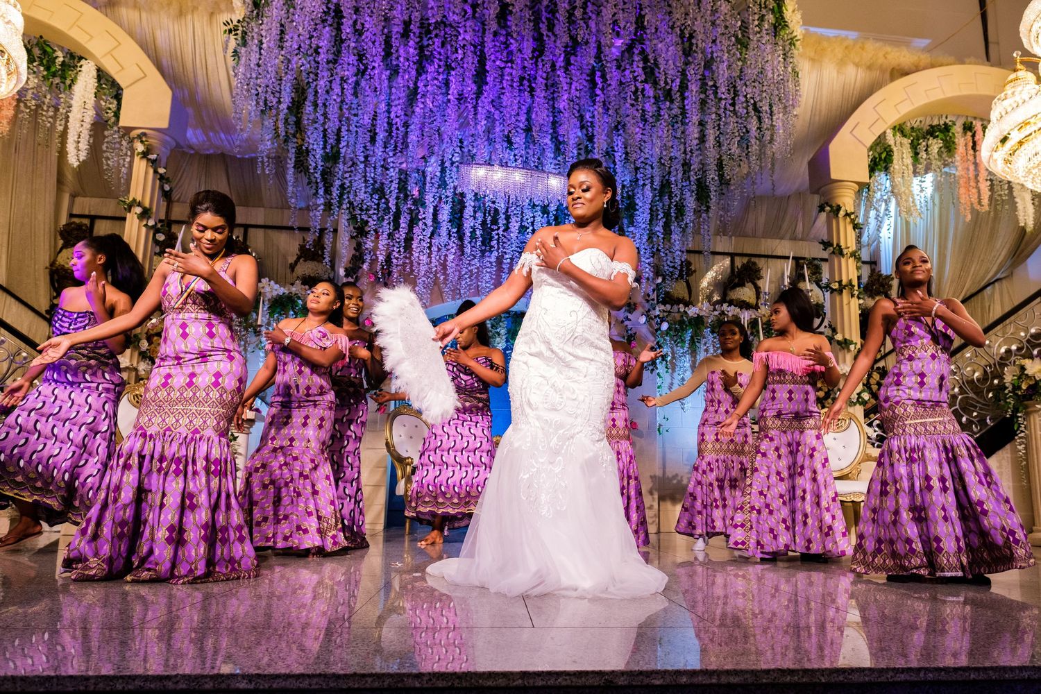 Wedding reception with purple wisteria decorations hanging from ballroom ceiling.