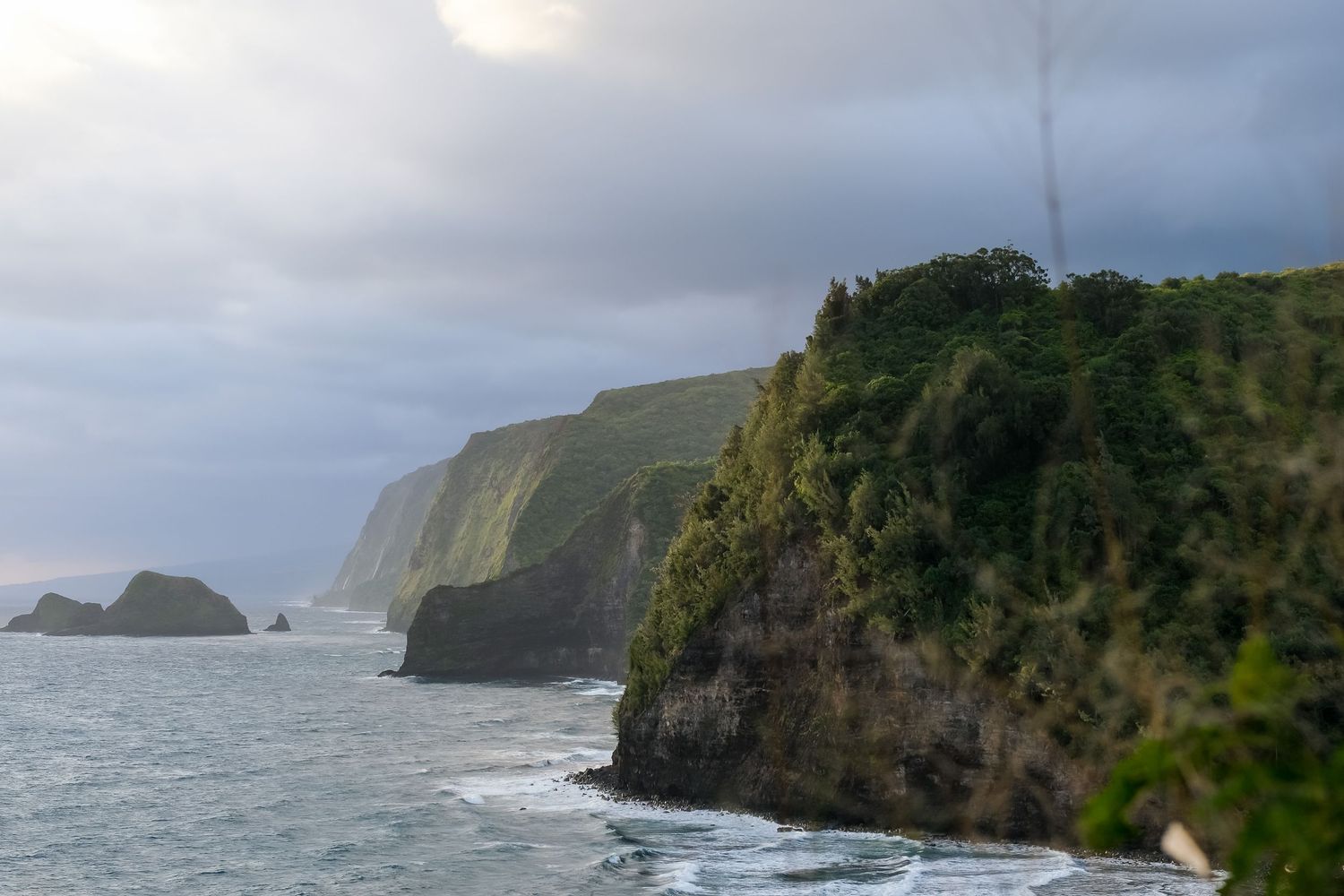 Dramatic coastal landscape with rugged cliffs and crashing waves along the Pacific Ocean shoreline.