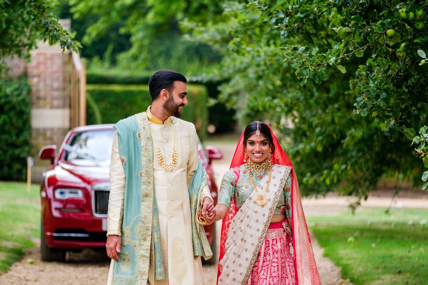 Traditional Indian wedding couple posing in a lush garden setting with elegant outfits.