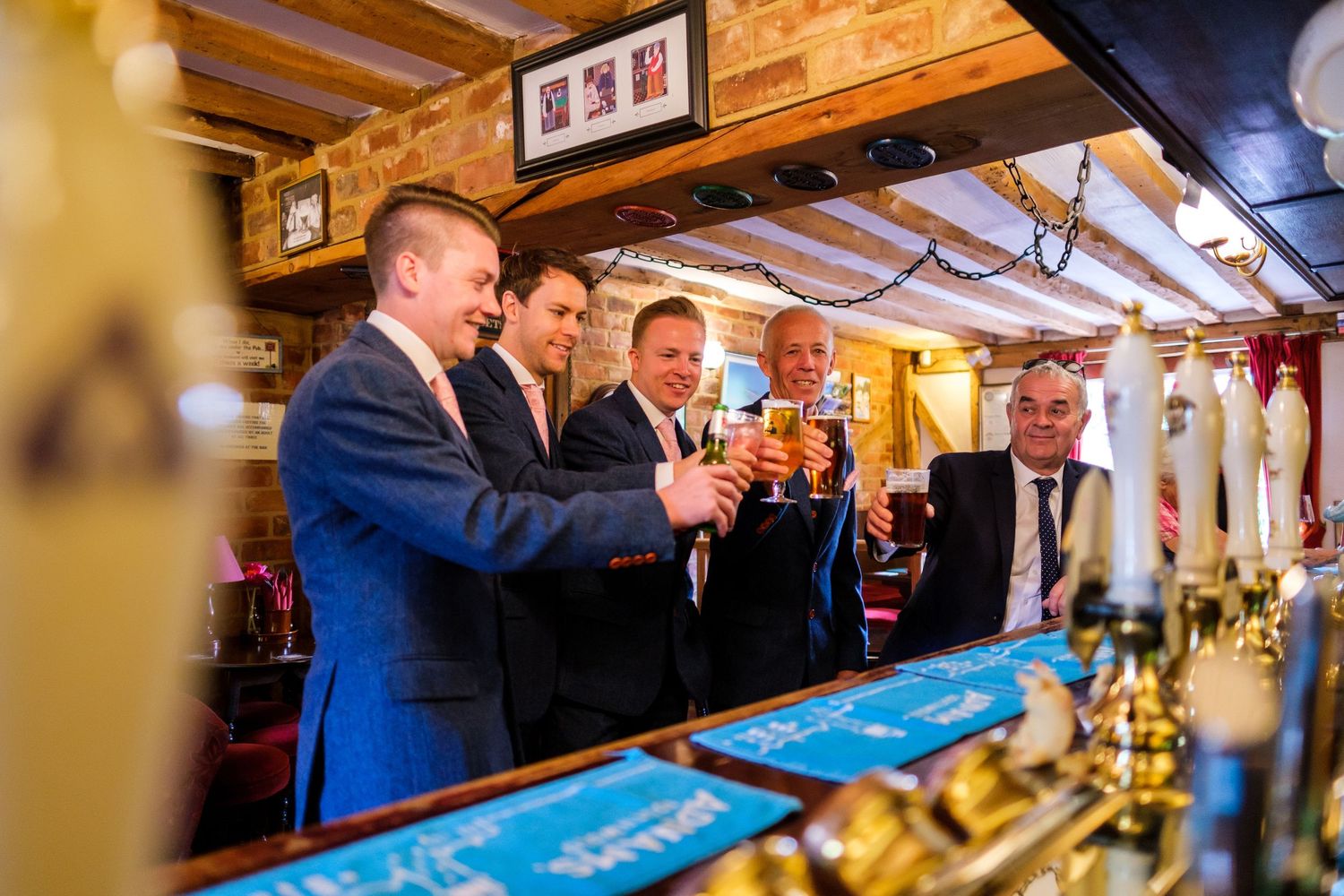 Group gathered around wooden bar counter during wedding reception celebration.